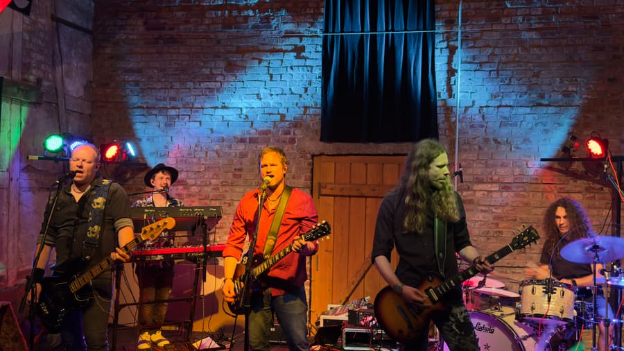 Losing Gravity performing as a full band in front of a brick wall stage